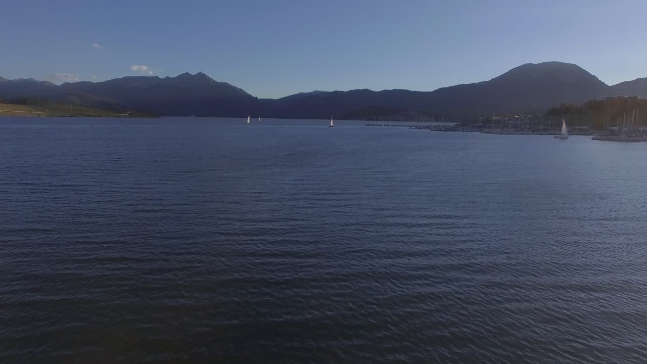 barcos de vela en el lago de las montañas rocosas durante la puesta de sol