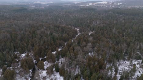 Aerial Flyover Of The Credit River Flowing Through A Forest Landscape During Winter In Caledon.