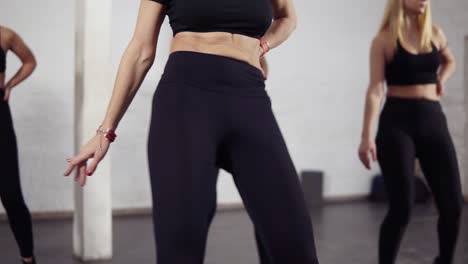sportive bodies of female dancers in black active wear learning bachata moves. groovy, fun, fitness