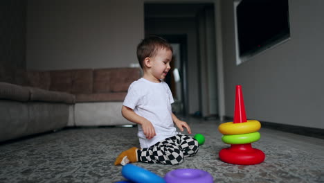 cute caucasian toddler building a pyramid incorrect. kid disassembles the toy and assembles it right.