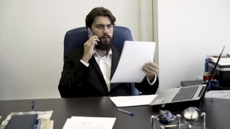 businessman on phone and reviewing documents