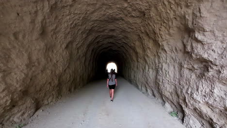 mulher caminhando por um túnel em direção ao caminho da montanha caminito del rey - câmera lenta