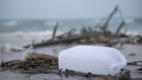 big plastic bottle on the beach polluting a dirty beach