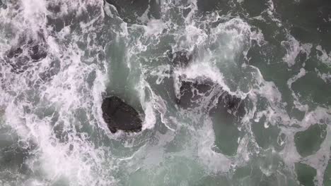 Drone-moving-away-from-ocean-waves-and-colliding-with-rocks