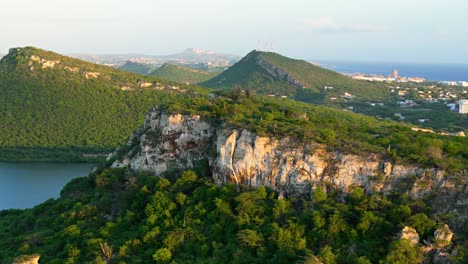 Aerial-trucking-pan-reveals-beautiful-city-of-Willemstad-Curacao-in-distance-behind-epic-rocky-cliffs