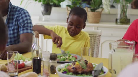 happy african american boy eating lunch with family at home