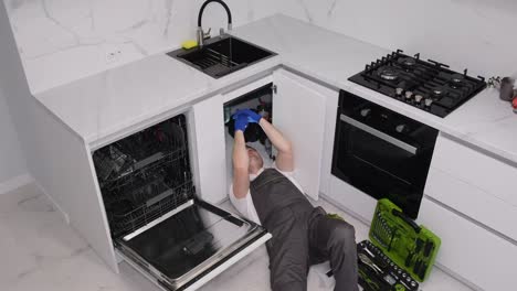 young plumber in uniform repairing sink in kitchen room a call to the home of a master plumber