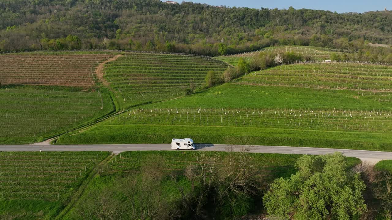 Pan drone shot of white van on a road during the day in Vipava, Inner Carniola, Slovenia