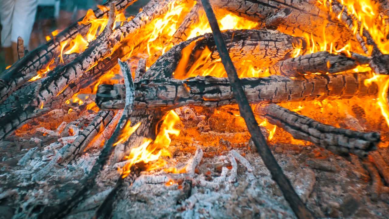 большой костер из ветвей горит ночью в лесу.