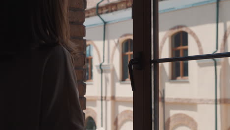 woman looking out of a window at a city