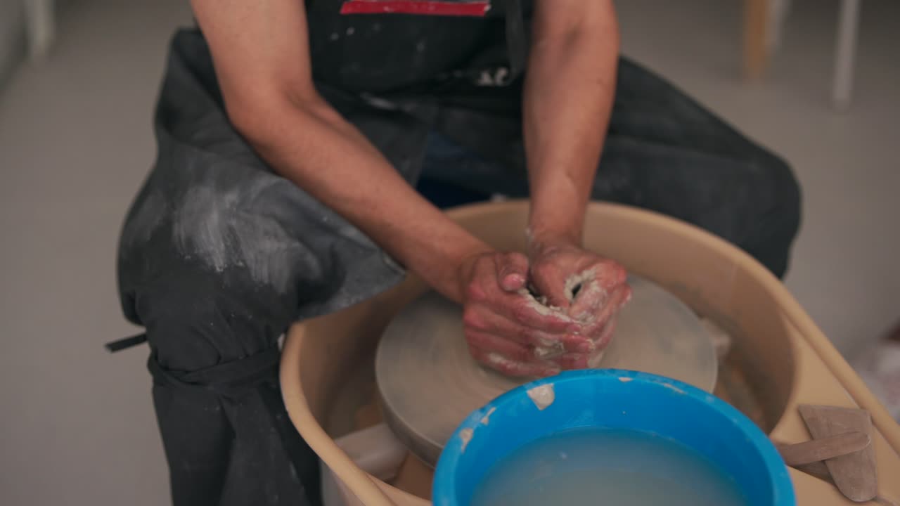 primer plano de manos moldeando arcilla en una rueda de cerámica