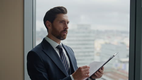 Financial-analyst-looking-documents-at-window-close-up.-Man-reading-statistic.