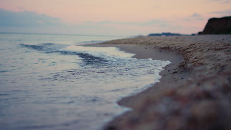 Peaceful-rocky-hill-coastline-view-at-morning-sunrise-pink-sky.-Sea-water-waves