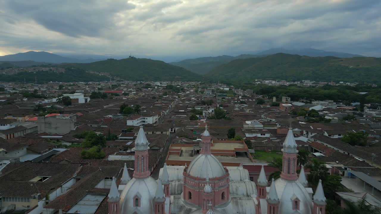 Aerial View of a Pink Church in a Town with Mountains