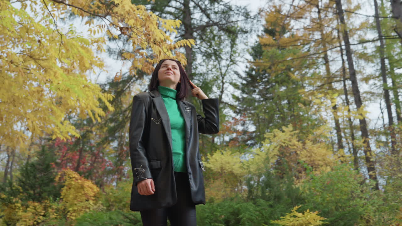 svart kvinne skinnjakke høst skog spasertur reflekterende stemning grønn genser, blader, ettertenksomt blikk, urban poet, fashion model, naturvandrer, kontemplativ reisende, overskyet himmel, frodig løvverk