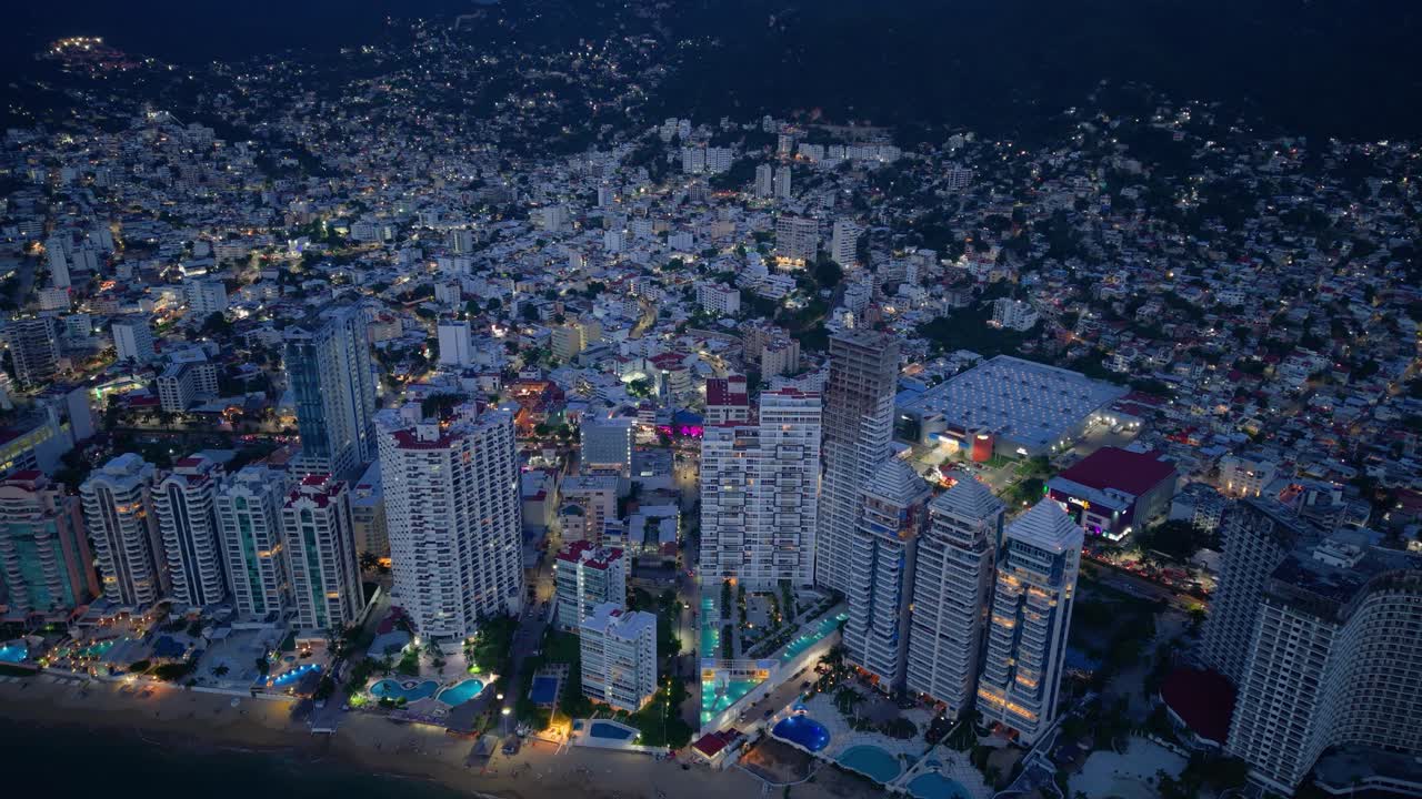 Upward drone shot over illuminated hotel zone in Acapulco, Mexico