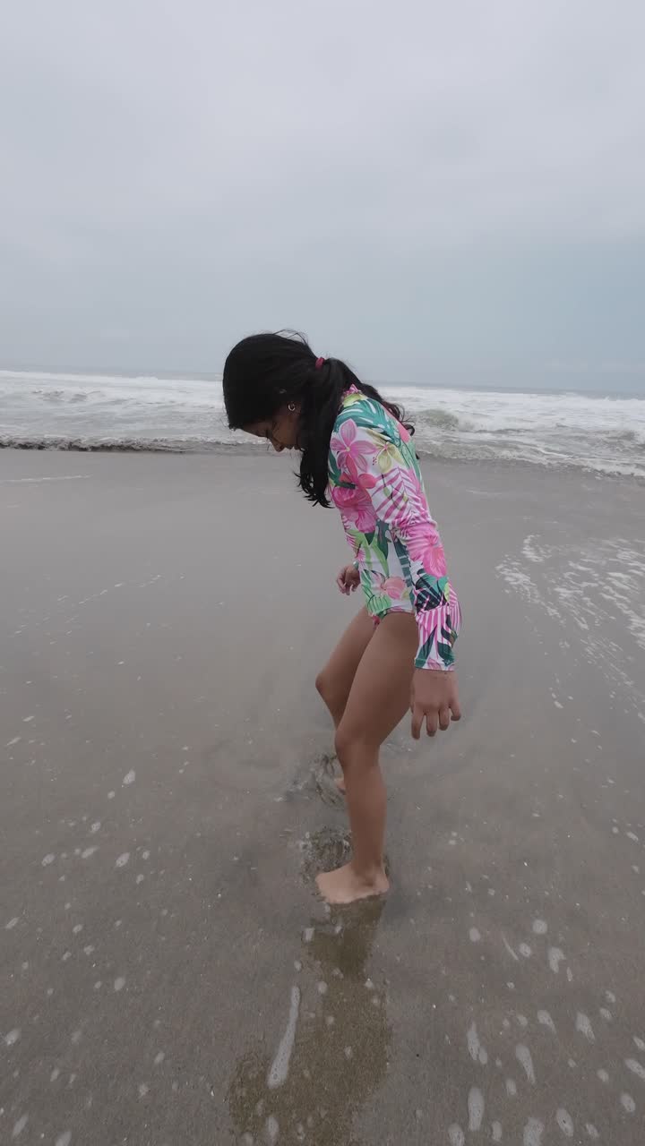 Niña jugando en las olas del mar en una playa de arena