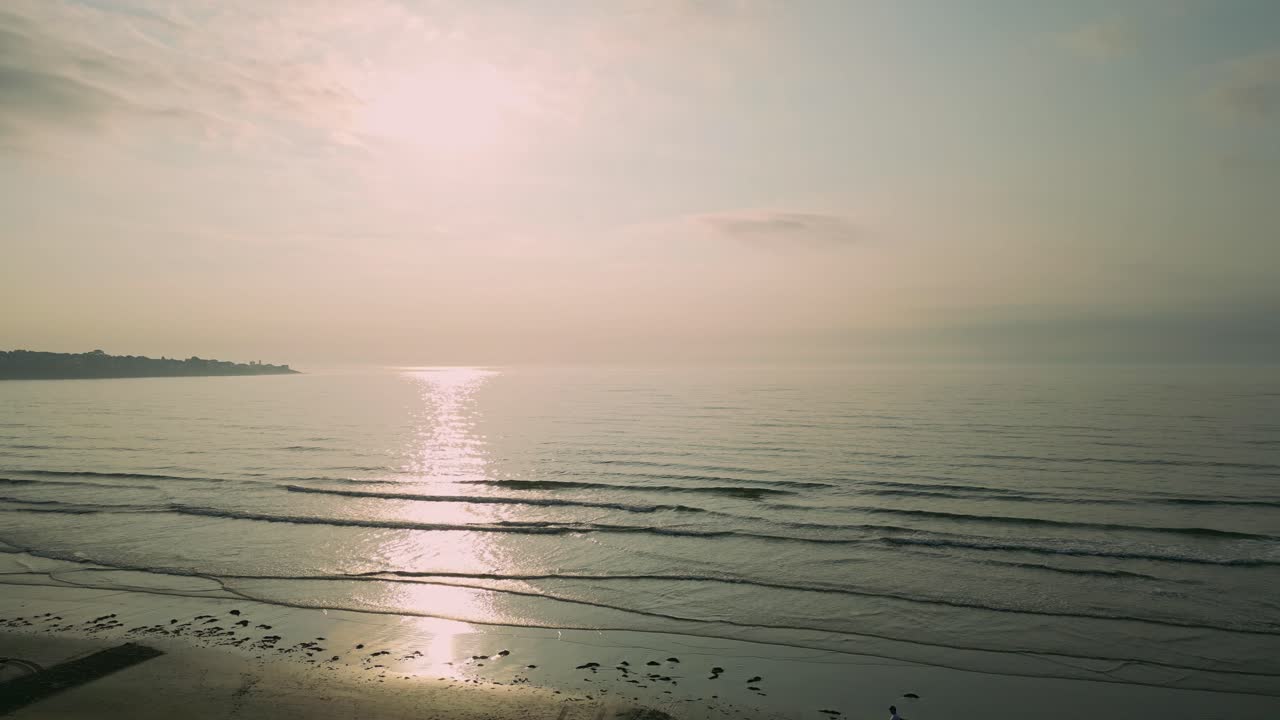 사람들이 개를 산책시키면서 요크 해변을 비추는 이른 아침 빛의 공중 촬영