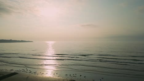 Aerial-shot-of-early-morning-light-illuminates-York-Beach-as-people-walk-their-dogs