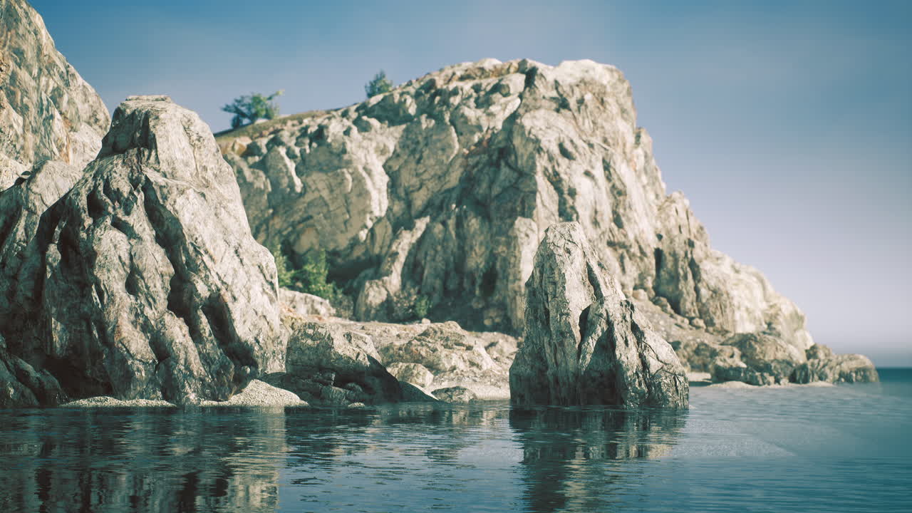 낮에는 은 하늘 아래 평온한 물과 함께 웅장한 바위 해안선