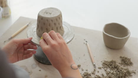 Manipulating soft clay with spnge, artisan seamlessly blends cup&#039;s sides, showcasing exquisite touch and craftsmanship