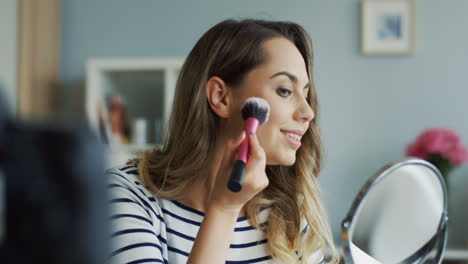 bonita bloguera de belleza grabando un video tutorial de maquillaje mientras aplica polvo con un cepillo