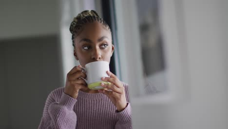 Nachdenkliche-Afroamerikanische-Frau,-Die-Kaffee-Trinkt-Und-Aus-Dem-Fenster-Schaut