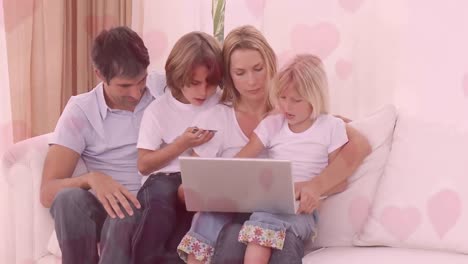 family using laptop while sitting on sofa