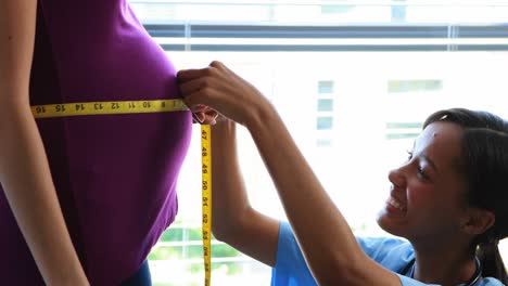 médico midiendo el vientre de una mujer embarazada en la sala