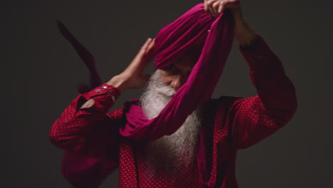 Low-Key-Studio-Lighting-Shot-Of-Senior-Sikh-Man-With-Beard-Tying-Fabric-For-Turban-Against-Dark-Background-11