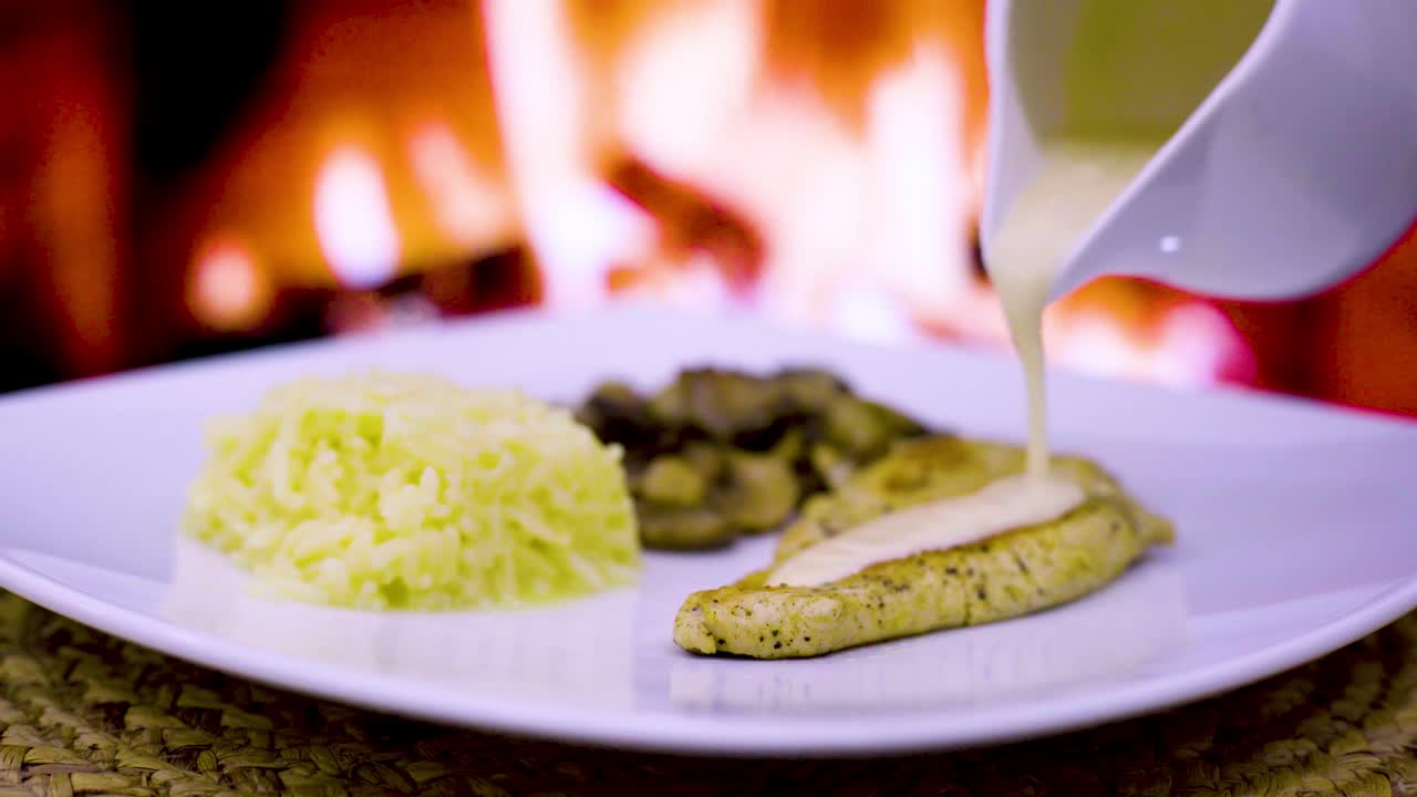 chuleta de pollo con crema y hongos, crema fresca, queso, arroz en un plato cuadrado con un fuego de leña en el fondo