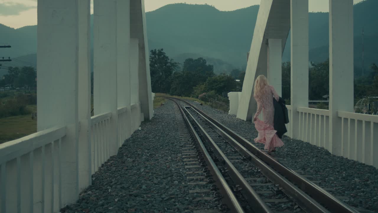 Woman Walking on Train Tracks Across Bridge