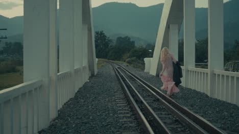 woman walking on train tracks across bridge