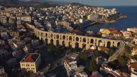 Aerial-of-ancient-Roman-aqueduct-next-to-the-ocean-in-Kavala,-Greece-at-sunset