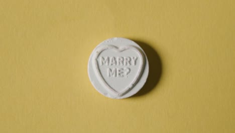 heart candy with marry me message on yellow background