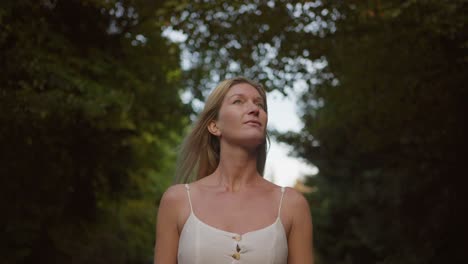 beautiful blond woman in white dress walking in autumn forest, portrait shot