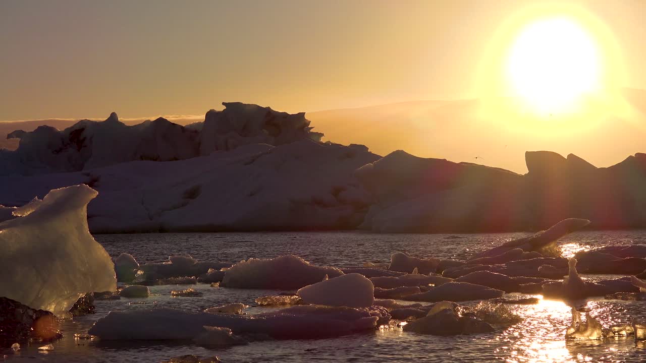 Midnight sun sets in the frozen Arctic Jokulsarlon glacier lagoon in Iceland suggesting global warming