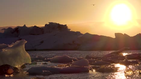 el sol de medianoche se pone en la congelada laguna glaciar jokulsarlon del ártico en islandia, lo que sugiere el calentamiento global