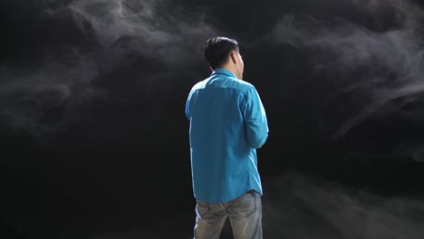 man in blue shirt, back view, with smoke background