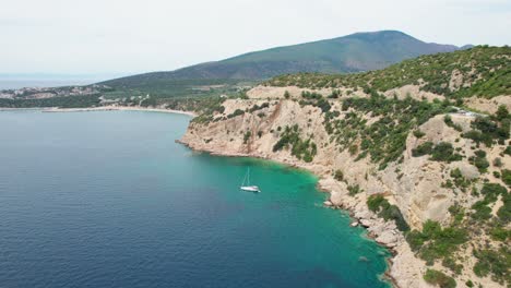 top down view over a rocky seaside, anchored sail boat, turquoise water, lush vegetation, fari beach, thassos island, greece