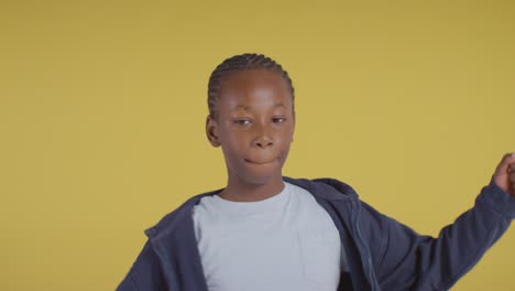 Studio-Portrait-Of-Hyperactive-Boy-Smiling-And-Swinging-Arms-Against-Yellow-Background