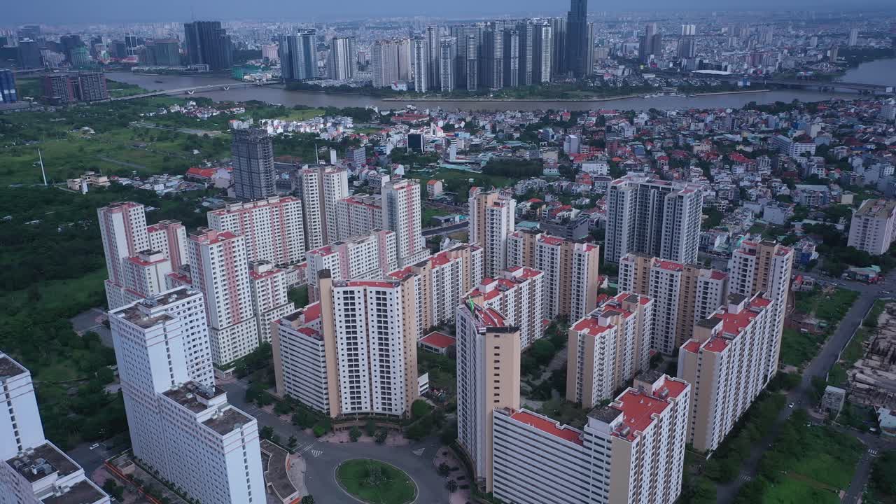 Aerial fly in over large modern residential development with city skyline in background on a sunny day in Ho Chi Minh City, Vietnam
