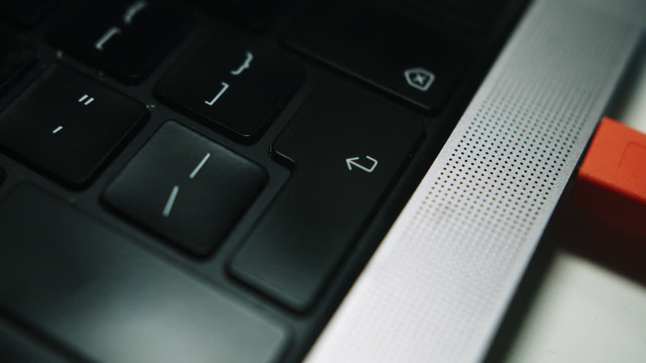 Beautiful slow motion close-up shot of a man pressing the “Enter” key on a MacBook Pro laptop keyboard in his bedroom.