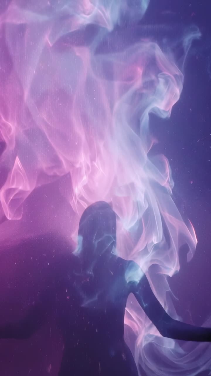 Vertical video: Colored smoke intensifying, silhouette figure lifting arms, swirling in studio