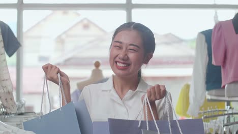 cheerful young asian woman with the shopping bags dancing celebrating be able to buying clothes while shopping at the boutique