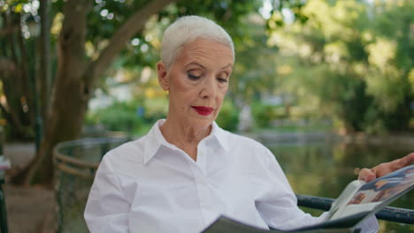 pensioner reading newspaper park cafe closeup. elegant mature lady rest outdoors