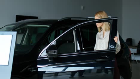 woman looking at a new black suv in a car dealership