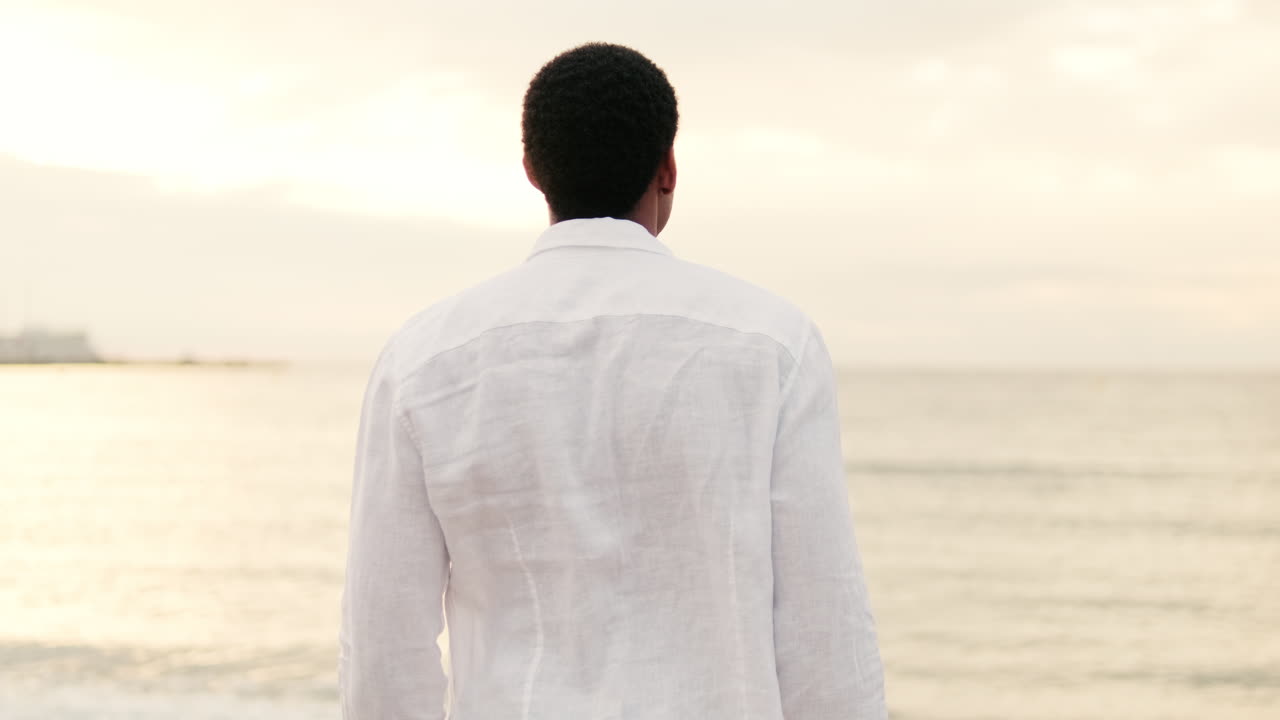 Man Standing on Beach Looking at the Sea at Sunset