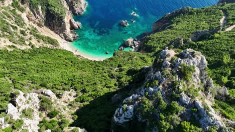 Toma-Aérea-De-La-Playa-De-Giali-En-Corfú,-Exuberante-Vegetación-Que-Rodea-Las-Aguas-Turquesas,-Día-Soleado