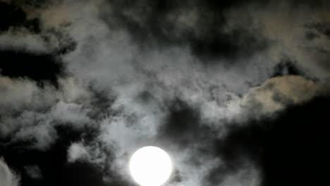 a bright full moon rises above swiftly moving clouds in the night sky 1